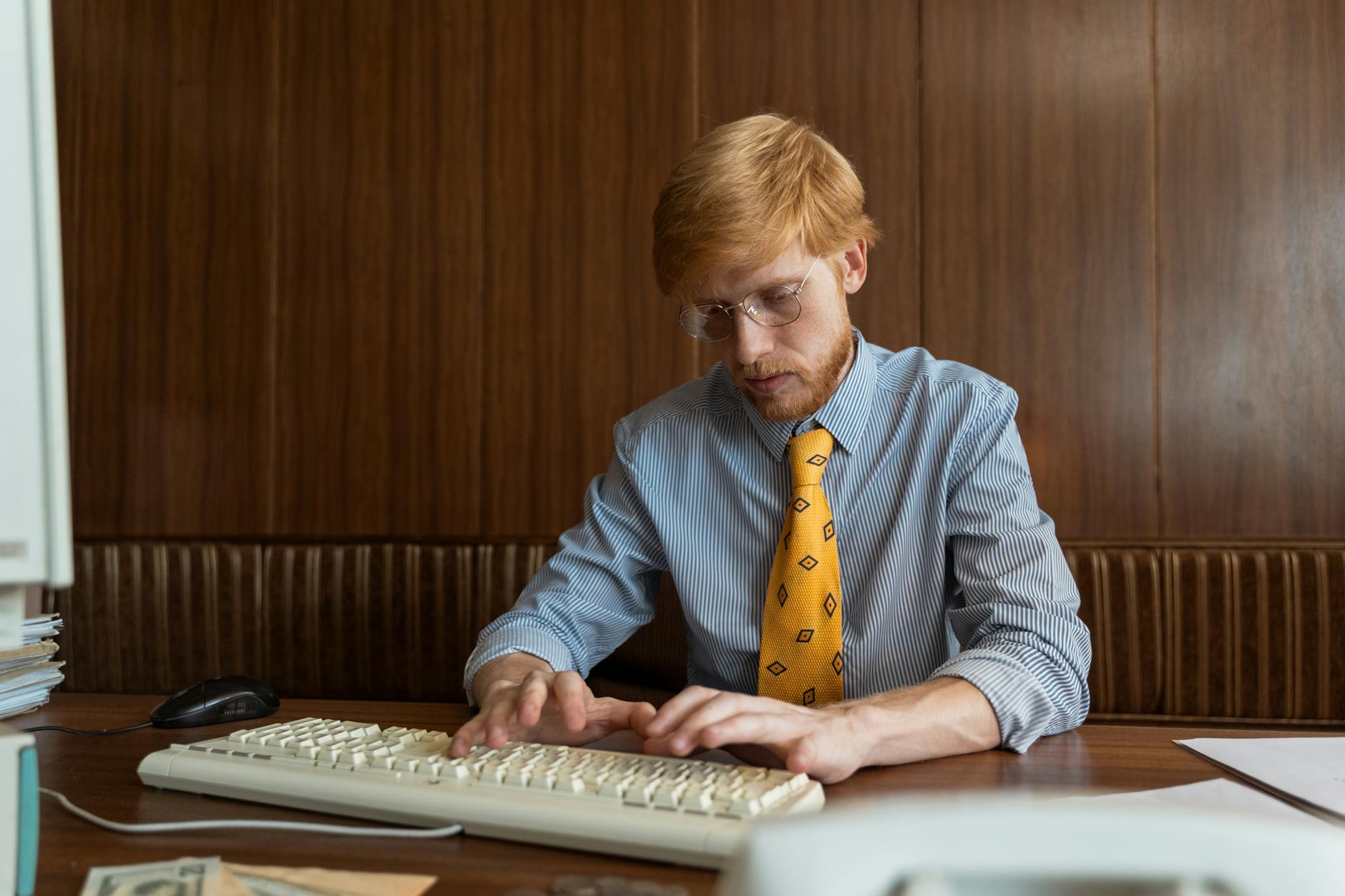 Mężczyzna skupiony przy biurku, piszący na klawiaturze komputera