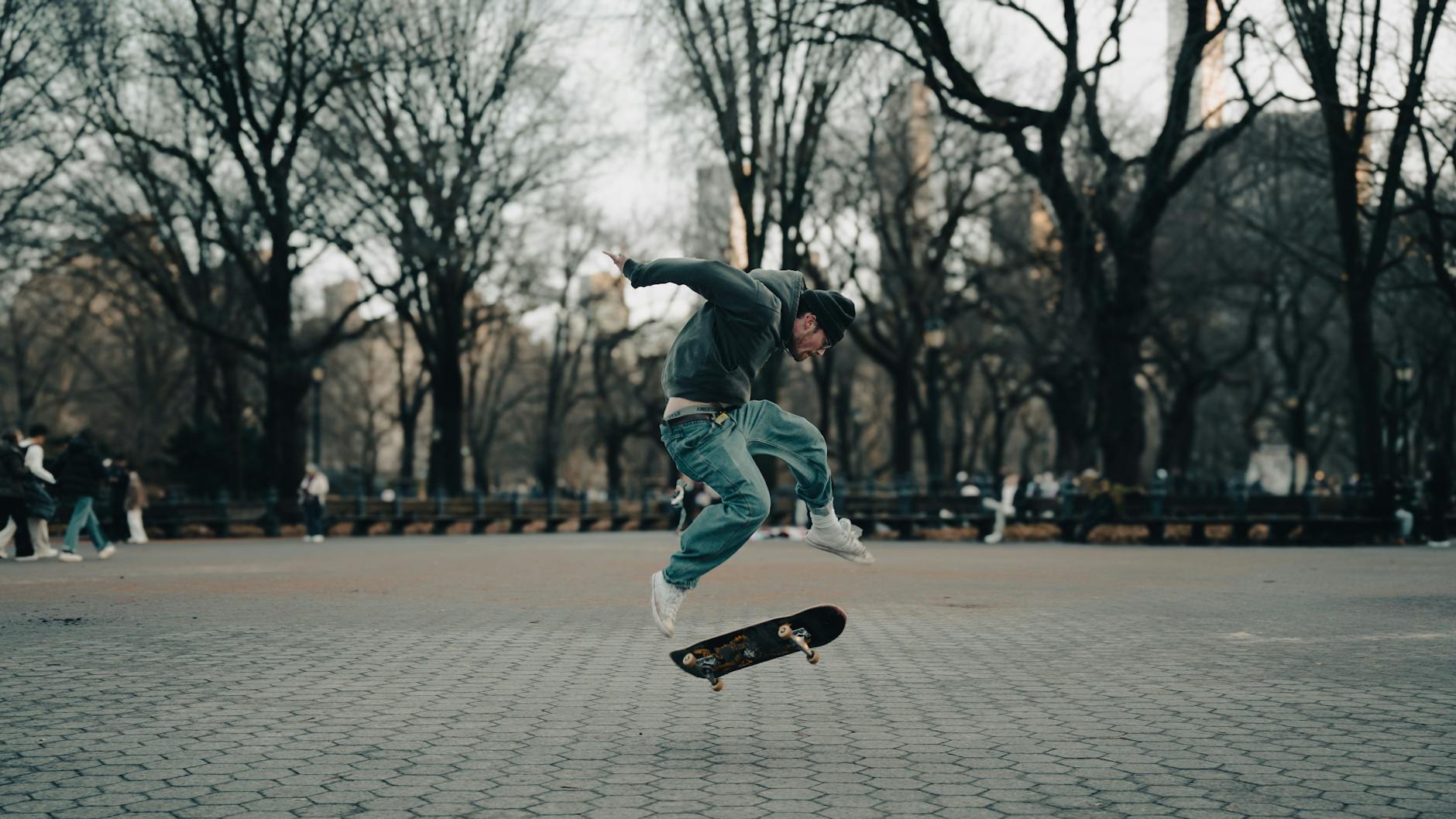 Skater wykonuje trik na ulicznej przeszkodzie w zimowym Central Parku