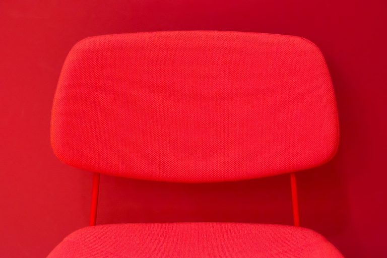 Czerwone krzesło z tapicerowanym oparciem w minimalistycznym wnętrzu